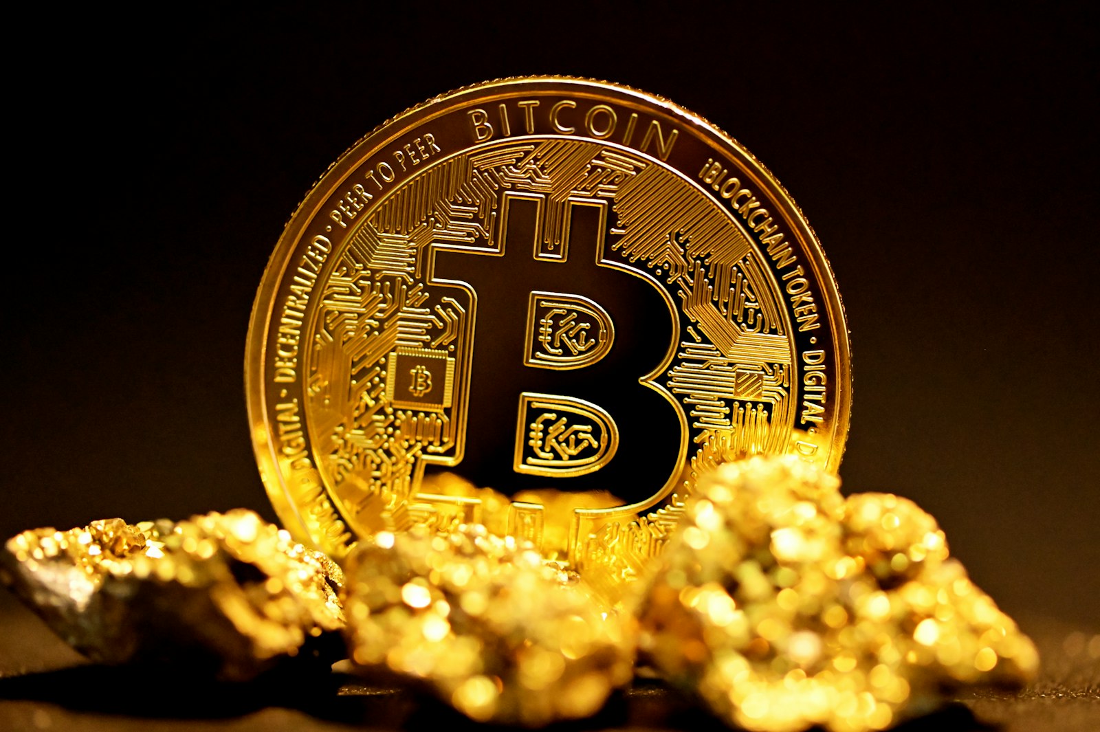 A single physical Bitcoin coin standing on a dark reflective surface