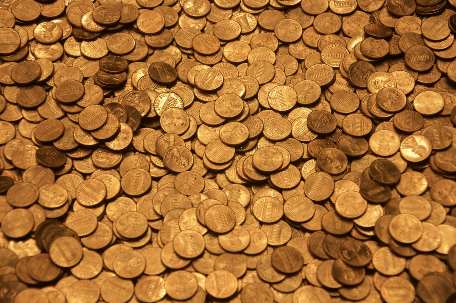 A small pile of gold coins catching warm light against a dark background
