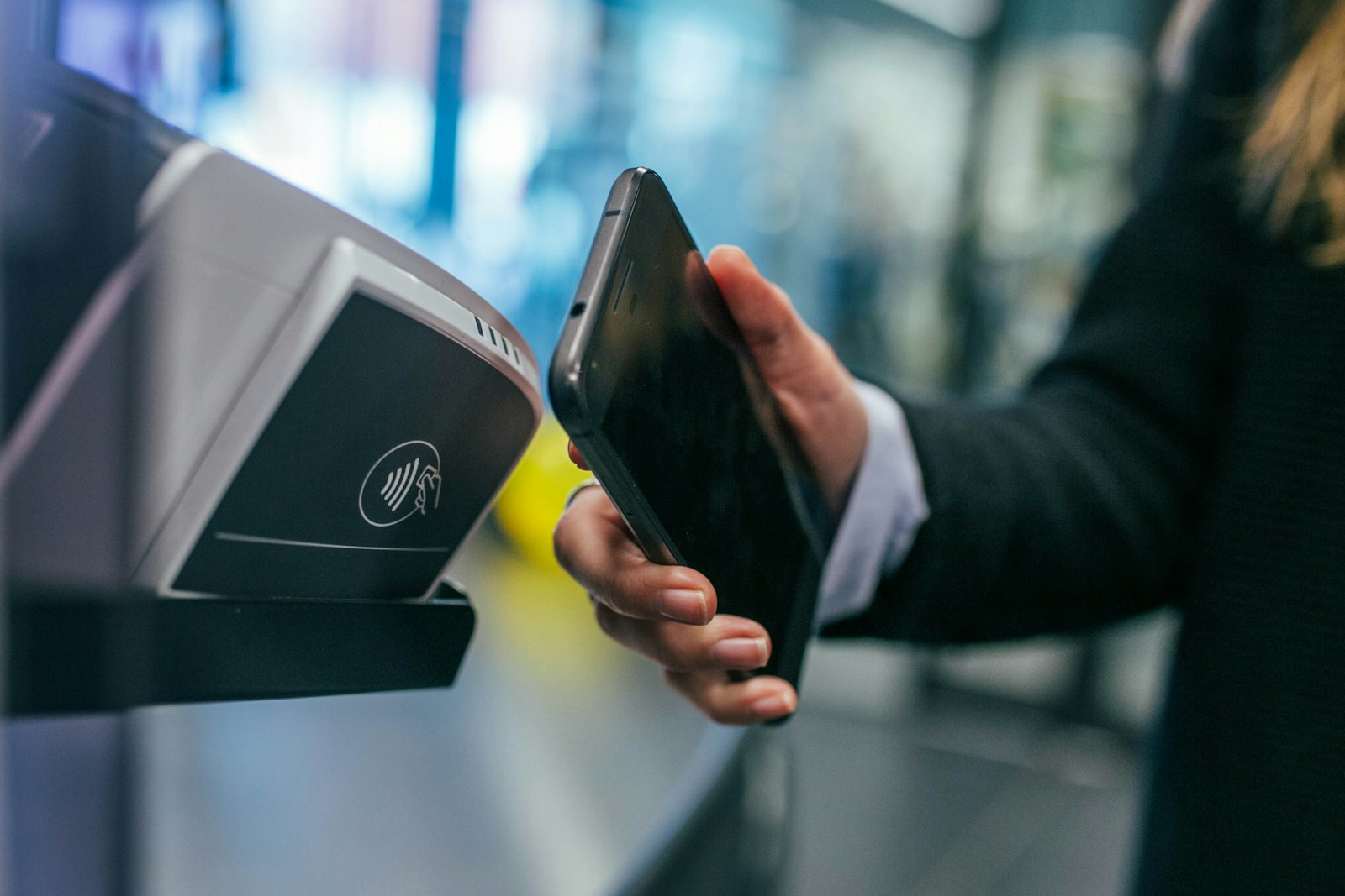 A hand tapping a card against a contactless payment terminal in a shop