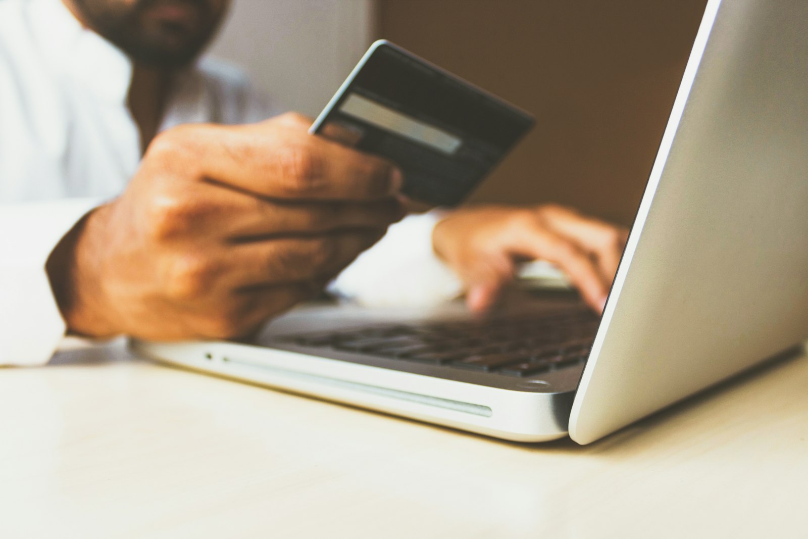 A person holding a payment card while shopping online on a laptop